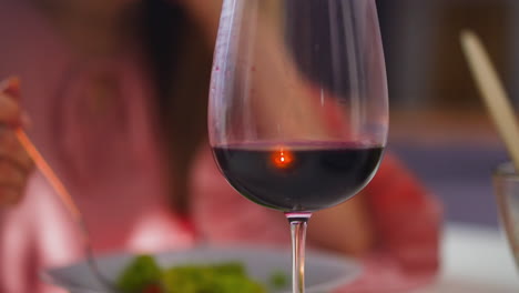 collectible red wine on table against woman eating salad