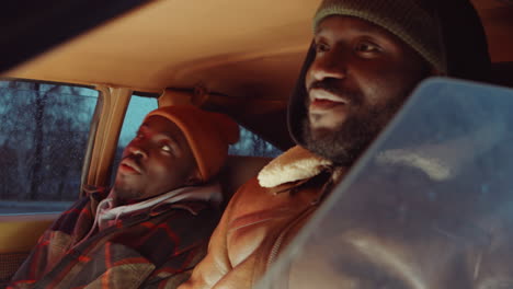 two black friends having talking while sitting in car in evening