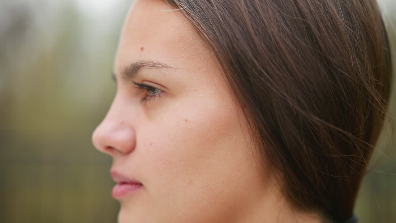 Primer plano del rostro de una joven mostrando granos, textura de piel natural, rasgos suaves, toma casual al aire libre, imperfecciones de belleza, piel real, juventud, belleza natural, toma de belleza.