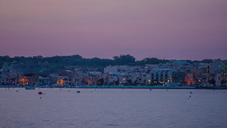 shot of waterfront city buildings in gzira, il-gzira, malta as sun rays lighting up the morning sky in timelapse