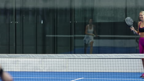 woman in sportswear playing padel tennis, smiling and enjoying game on indoor court