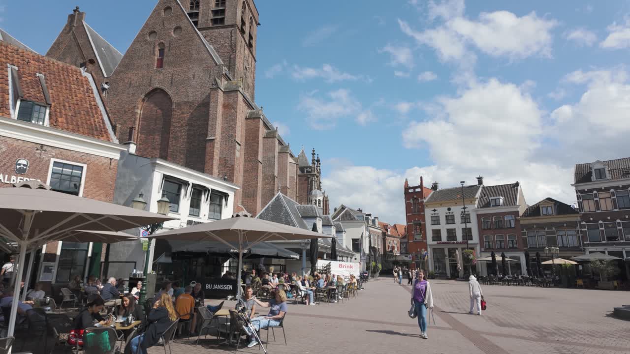 Bustling town square, Stadsplein de Hof, in Amersfoort with people strolling and historic buildings under blue sky