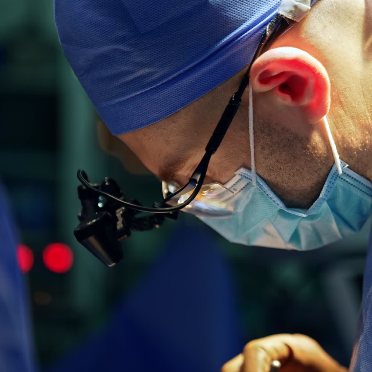 Male surgeon in uniform, cap, mask and device glasses. Side view portrait of neurosurgeon in the operational theater