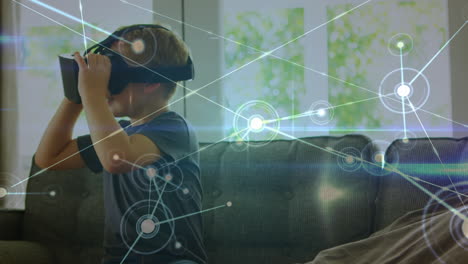 red de conexiones a través de un niño caucásico con auriculares vr sentado en el sofá en casa