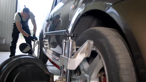 mechanic performing wheel alignment on a car in a service garage