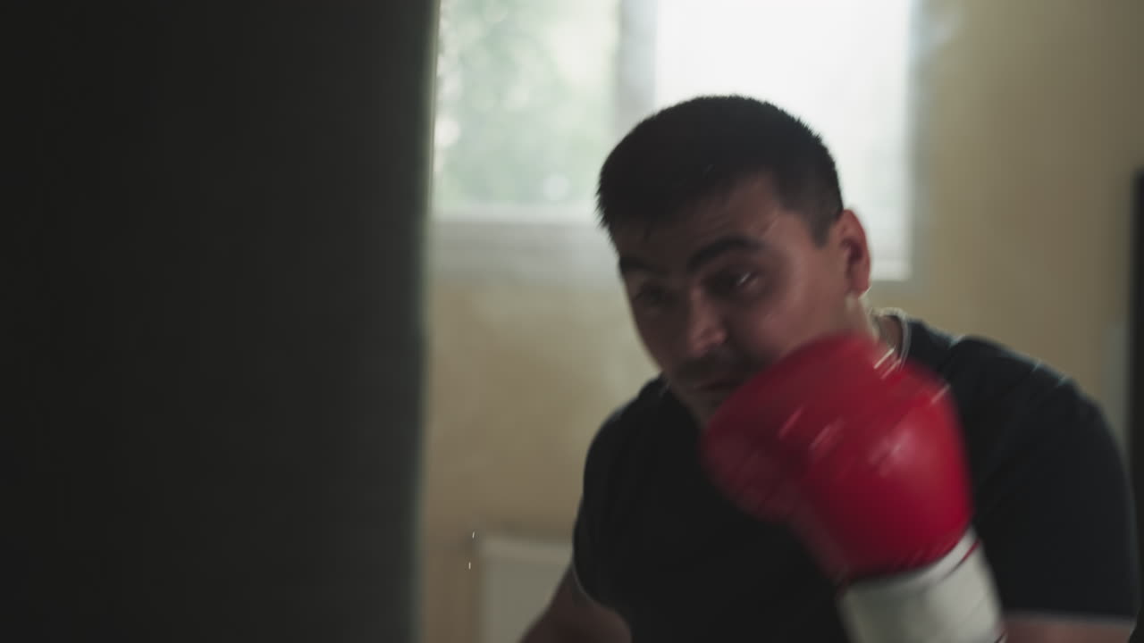 el boxeador golpea una bolsa pesada en un club deportivo. el deportista profesional hace ejercicios con equipos de lucha en el gimnasio en cámara lenta. campeón de artes marciales