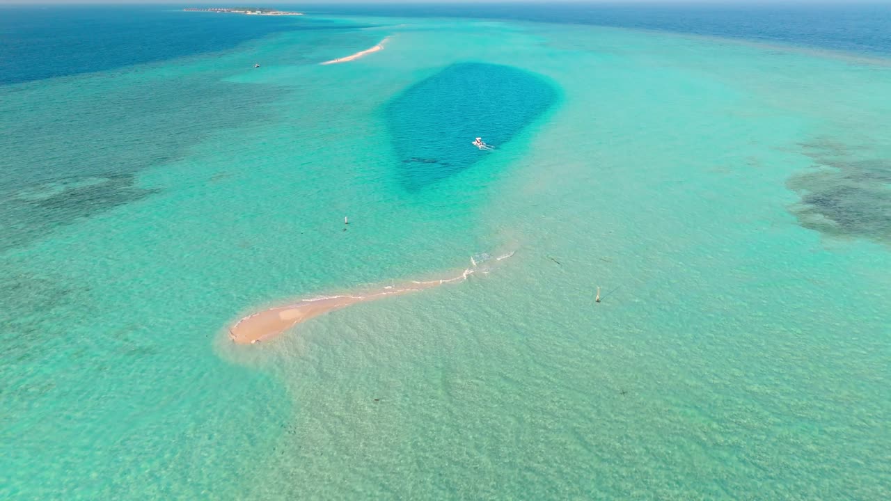 An awe-inspiring aerial drone view captures the Rasdhoo Sandbanks glowing under the soft, golden light of sunset in the Maldives.