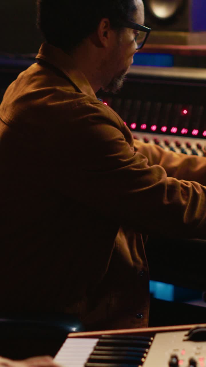Musicista che suona la tastiera e mixa musica in uno studio di registrazione