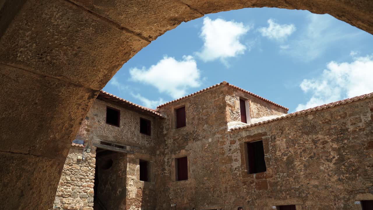 Panning left shot of the old historic stone buildings from under an archway inside of the famous tourist attraction Natal Reis Magos military fort in Rio Grande do Norte, Brazil on a warm summer day