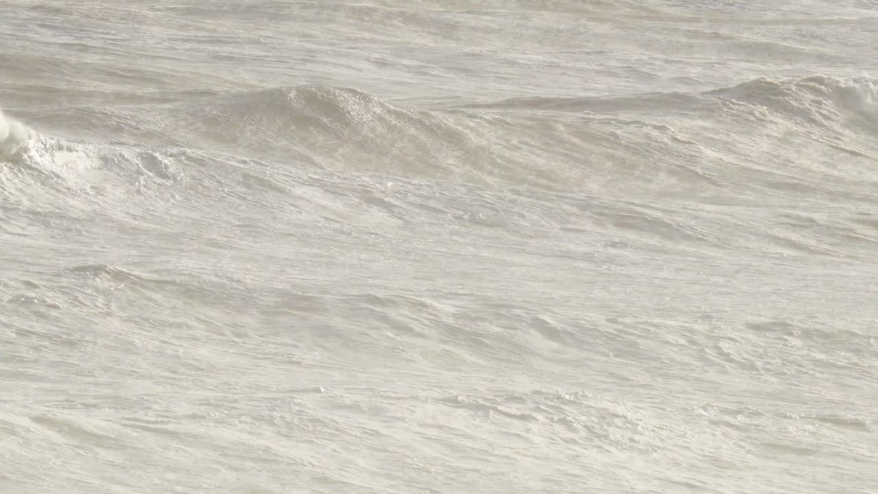 Dynamic ocean waves crash against the shore, captured in natural light, showcasing the power and beauty of the sea