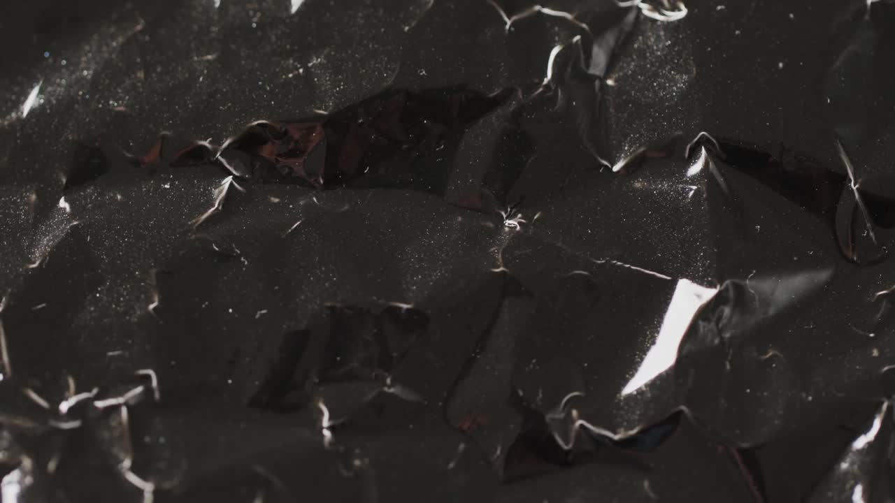 Close-up de saco de lixo plástico preto amassado em câmera lenta