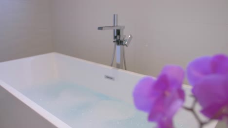 Beautiful-fake-flower-in-front-of-a-filled-warm-bath-tub-with-foam