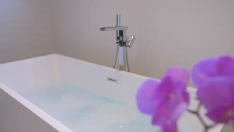hermosa flor falsa frente a una bañera de baño caliente llena de espuma