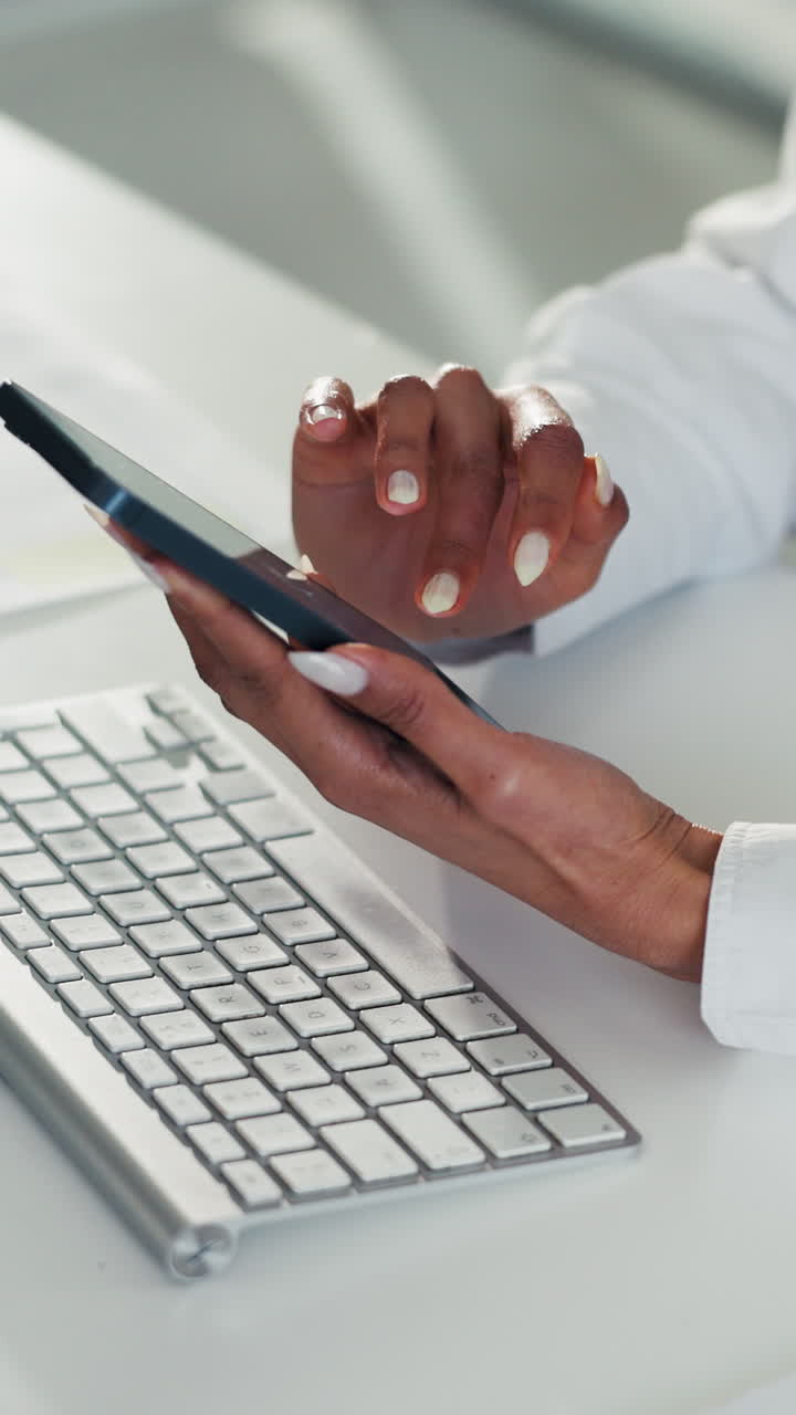Primo piano delle mani che usano smartphone e tastiera su una scrivania