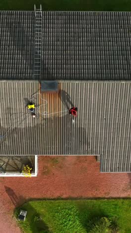 aerial portrait shot above a woman pressure washing a house roof, autumn day