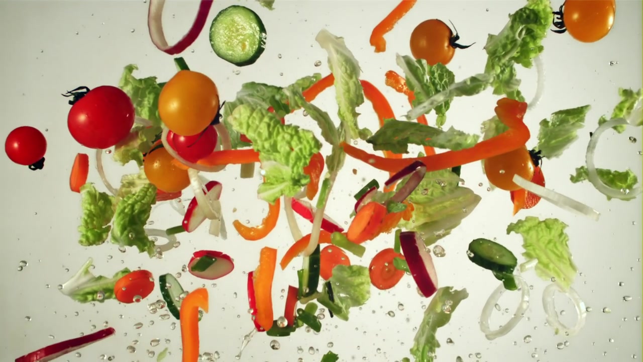 Verdure fresche tritate che cadono e galleggiano nell'acqua al rallentatore.