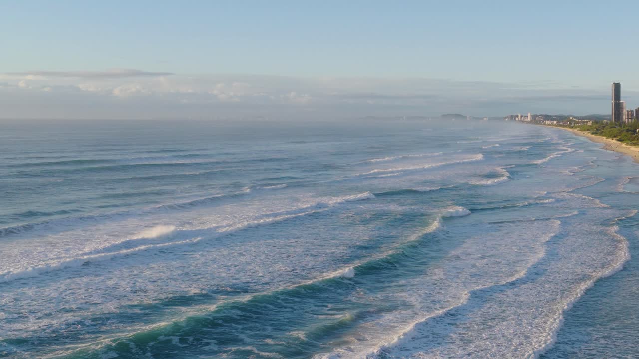 Aerial view of ocean waves rolling onto the Gold Coast beach under soft morning light, highlighting serene coastal beauty