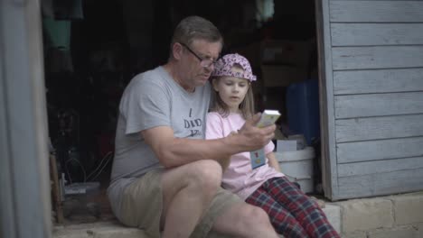 Grandfather-is-talking-and-discussing-educational-topics-with-his-granddaughter,-vintage-lens,-full-frame,-and-village-shot