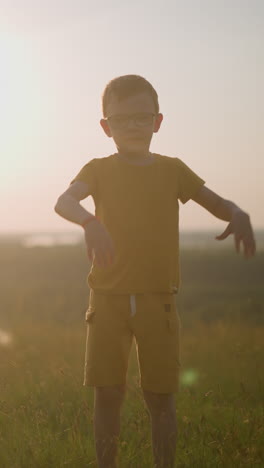 un niño joven, vestido de amarillo y con gafas, es capturado a mitad de salto en un campo cubierto de hierba durante una hermosa puesta de sol. la cálida luz dorada mejora la energía vibrante de la escena