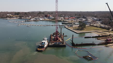 aerial static shot of a tug boat and barge with crane in harbor