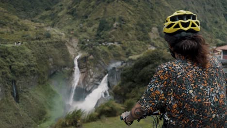 biker looking to the beautiful waterfalls during biking route tour in baños ecuador