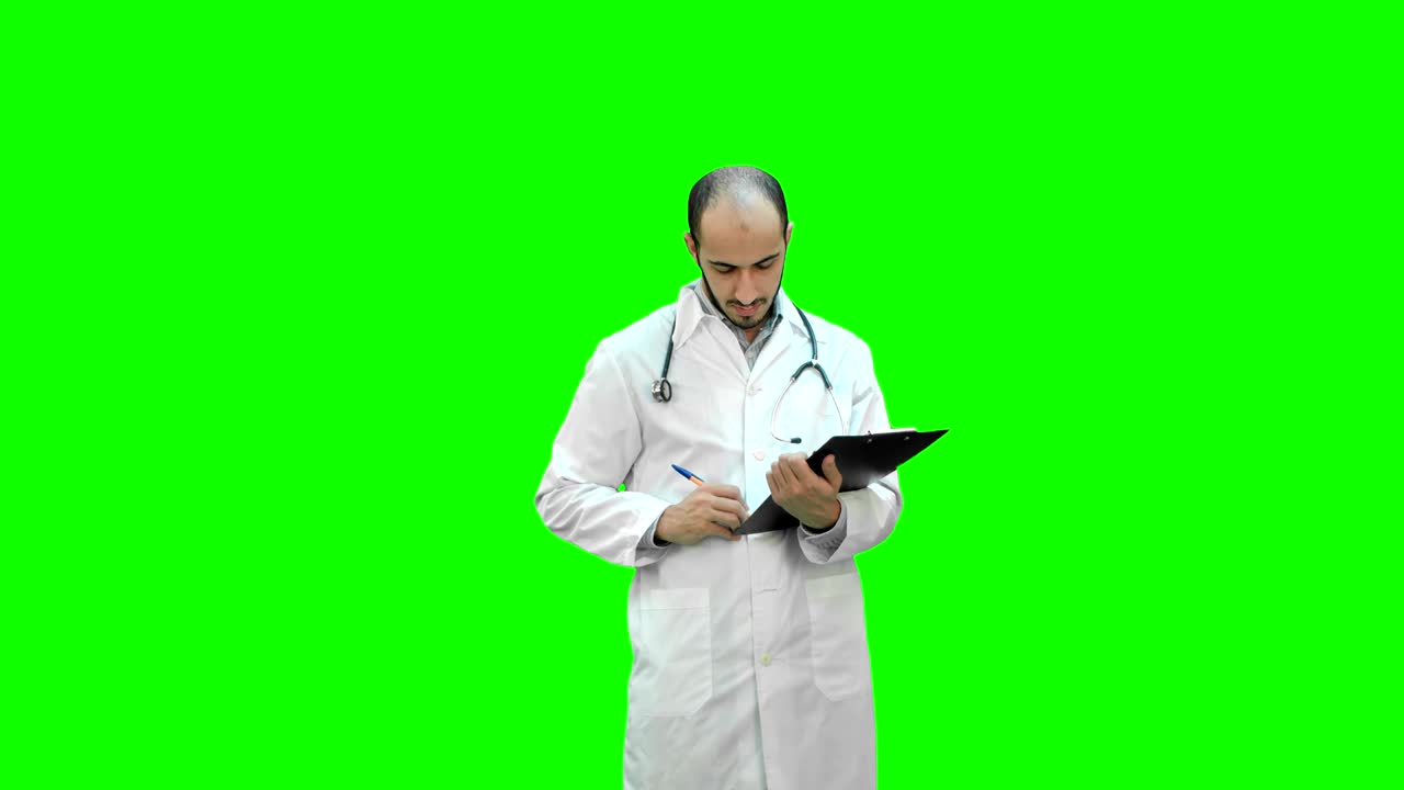 Medico uomo in camice bianco che compila un modulo di prescrizione su schermo verde, Chroma Key.