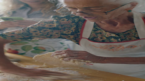 elderly woman kneading dough as granddaughter filming video with phone