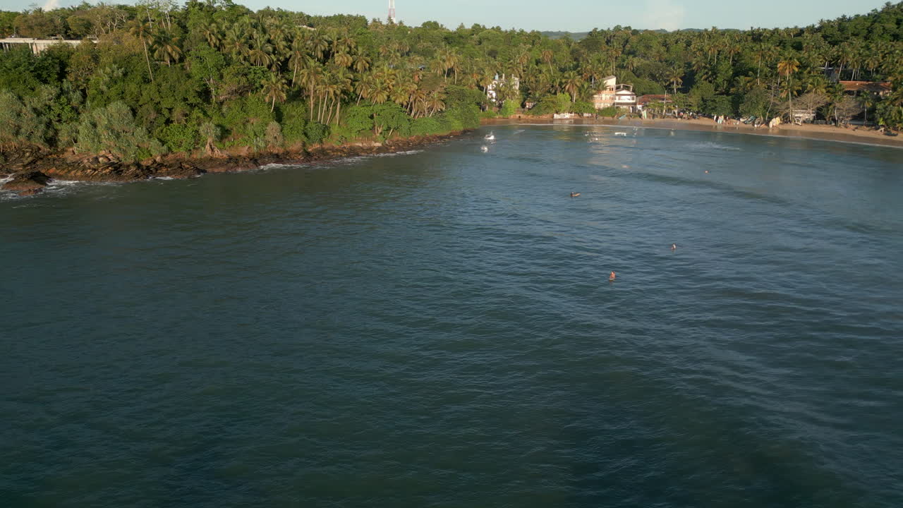 estableciendo una toma aérea de drone de la playa y la bahía de hiriketiya con surfistas en el agua