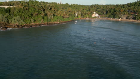 estableciendo una toma aérea de drone de la playa y la bahía de hiriketiya con surfistas en el agua