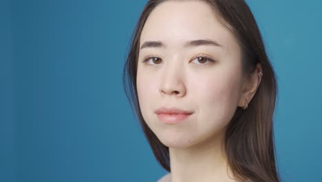 asian woman looking at camera. blue background.