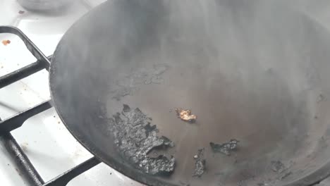 Sartén-Caliente-Humeante-En-Llamas-Carbonizada-De-Metal-Negro-Rociada-Con-Aceite-En-Preparación-Para-Cocinar-La-Plataforma-Rodante-A-La-Derecha