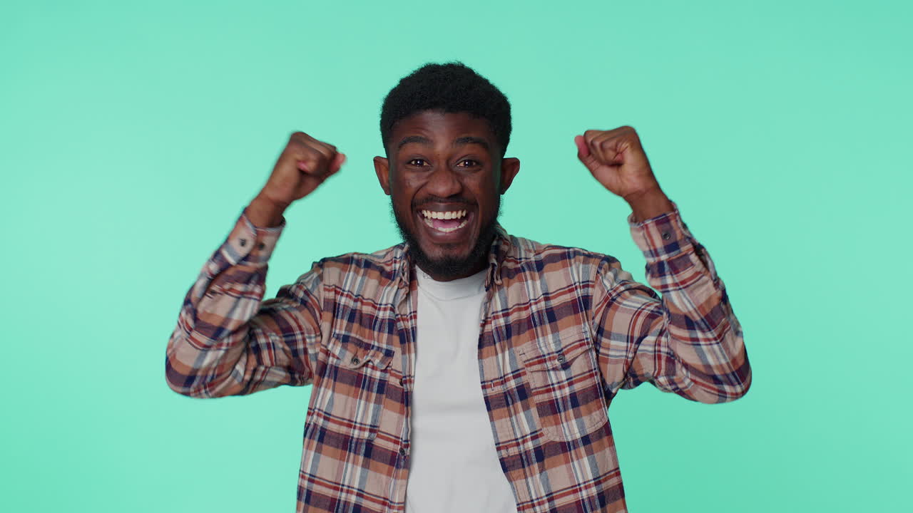 African american man shouting, raising fists in gesture I did it, celebrating success, winning