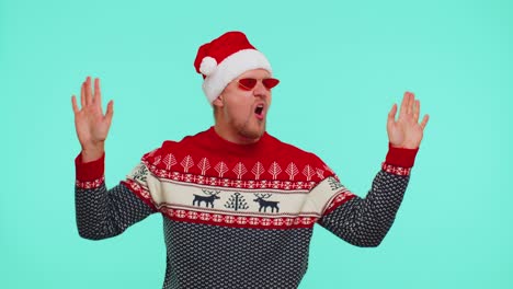 man in christmas sweater listening music via earphones, dancing disco fooling around having fun