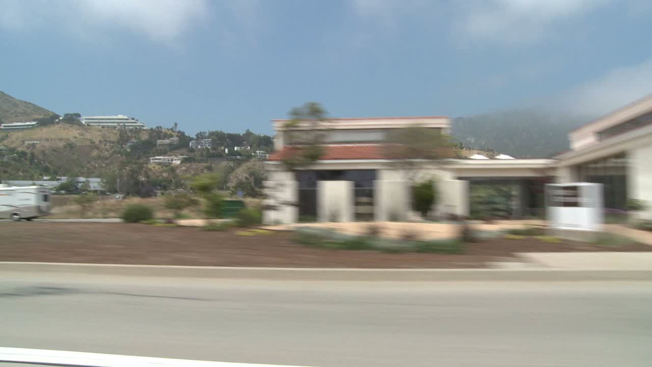 un automóvil viaja a lo largo de la autopista de la costa pacífica como se ve a través de la ventana lateral 5