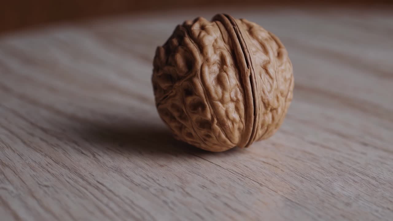 Video ravvicinato di una noce su una superficie di legno, ripreso da una angolazione bassa