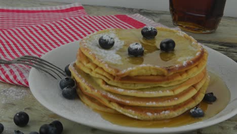 jarabe de arce en una pila de panqueques de avena. panqueques veganos y vegetarianos saludables con bayas y jarabe de acero. sabrosos alimentos dulces para el desayuno. panqueches en fondo rústico blanco