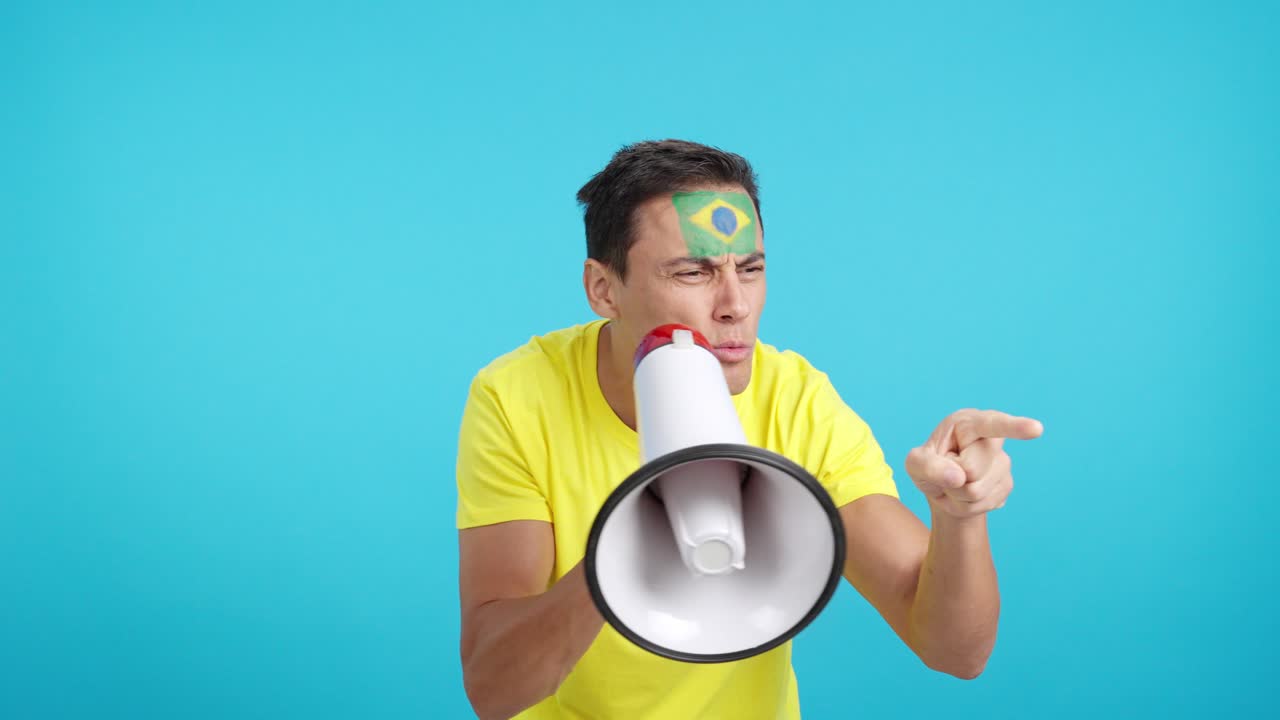 Excited man with brazilian flag on face using a megaphone