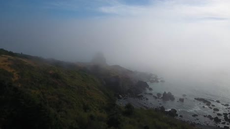 AERIAL:-Drone-shot-pushing-towards-a-mysterious-rock-formation-shrouded-by-fog