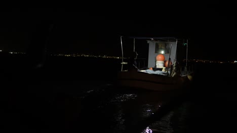 a small illuminated fishing boat flats on the open waters at night