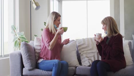 madre e hija hablando entre sí mientras beben café en casa