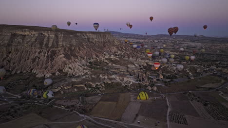 göreme turkey aerial v42 flyover fields of colorful hot air balloons rising up in the sky surrounded by rocky ridges of unique volcanic rock formations at dawn - shot with mavic 3 cine - july 2022