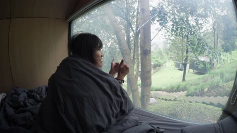 happy indonesian girl just woken up in a hut overlooking the jungle