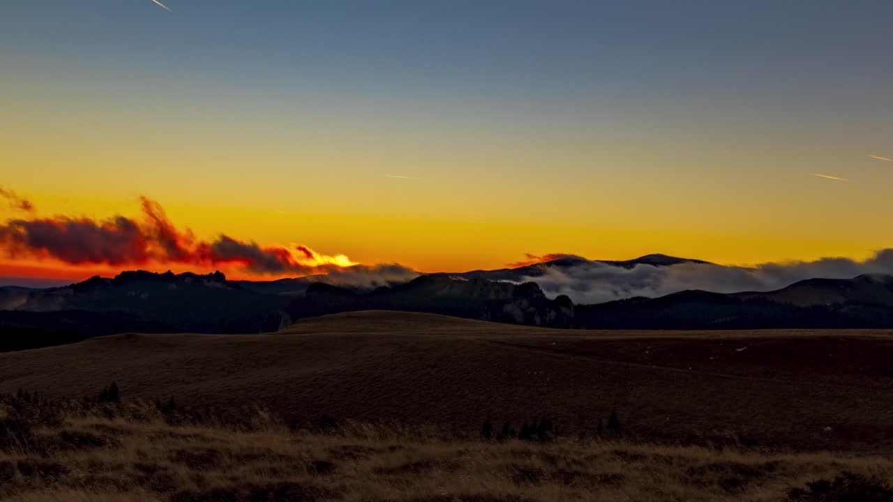 두꺼운 흰 구름이 소용돌이치는 산맥 위로 화려한 일몰, 주황색 일몰