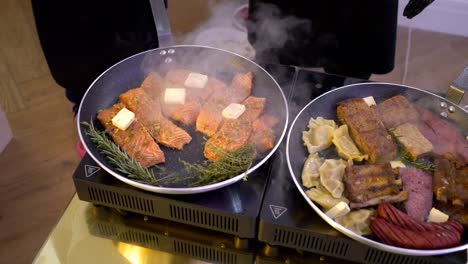 A-chef-is-live-cooking-pieces-of-salmon-and-pork-with-rosemary