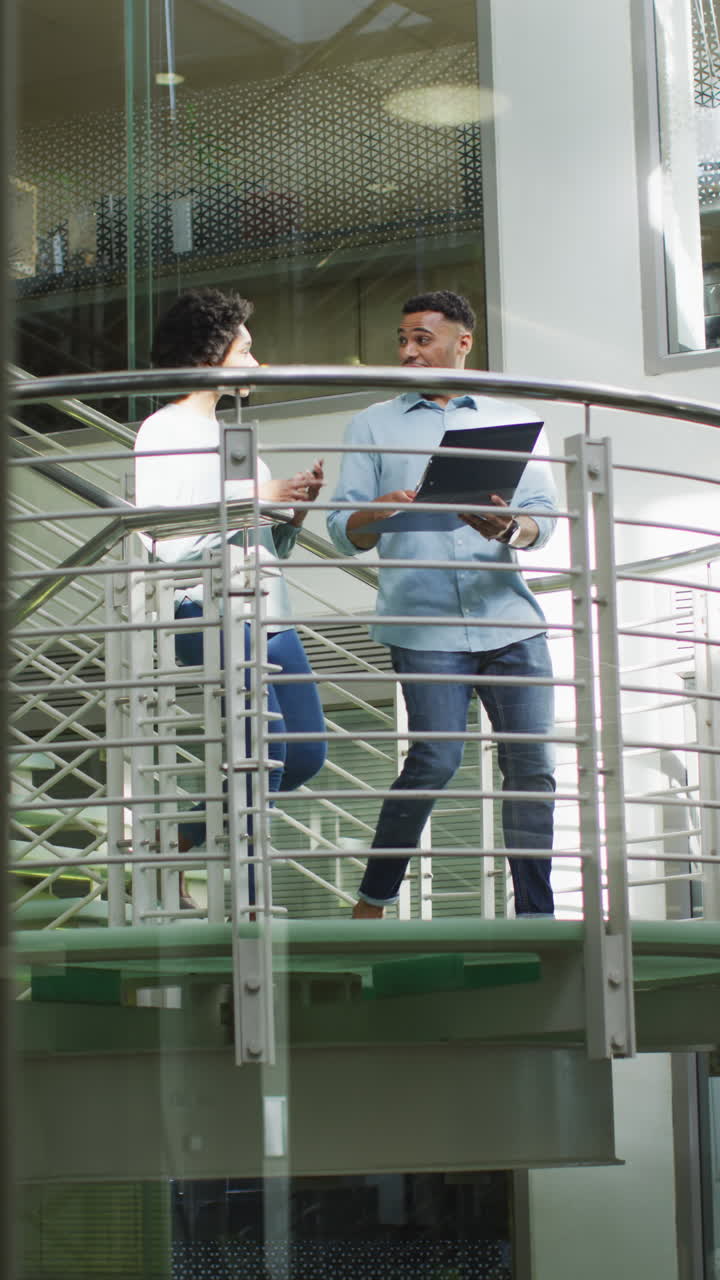 Video verticale di felici colleghi diversi (donna e uomo) che parlano sulle scale