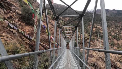 cruzando un puente de senderismo de metal con banderas de oración budista