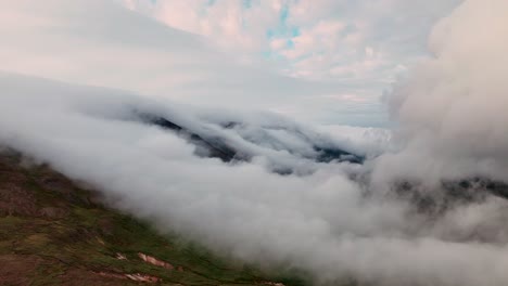 nubes rodando sobre las colinas de las montañas en el este de islandia durante la puesta de sol