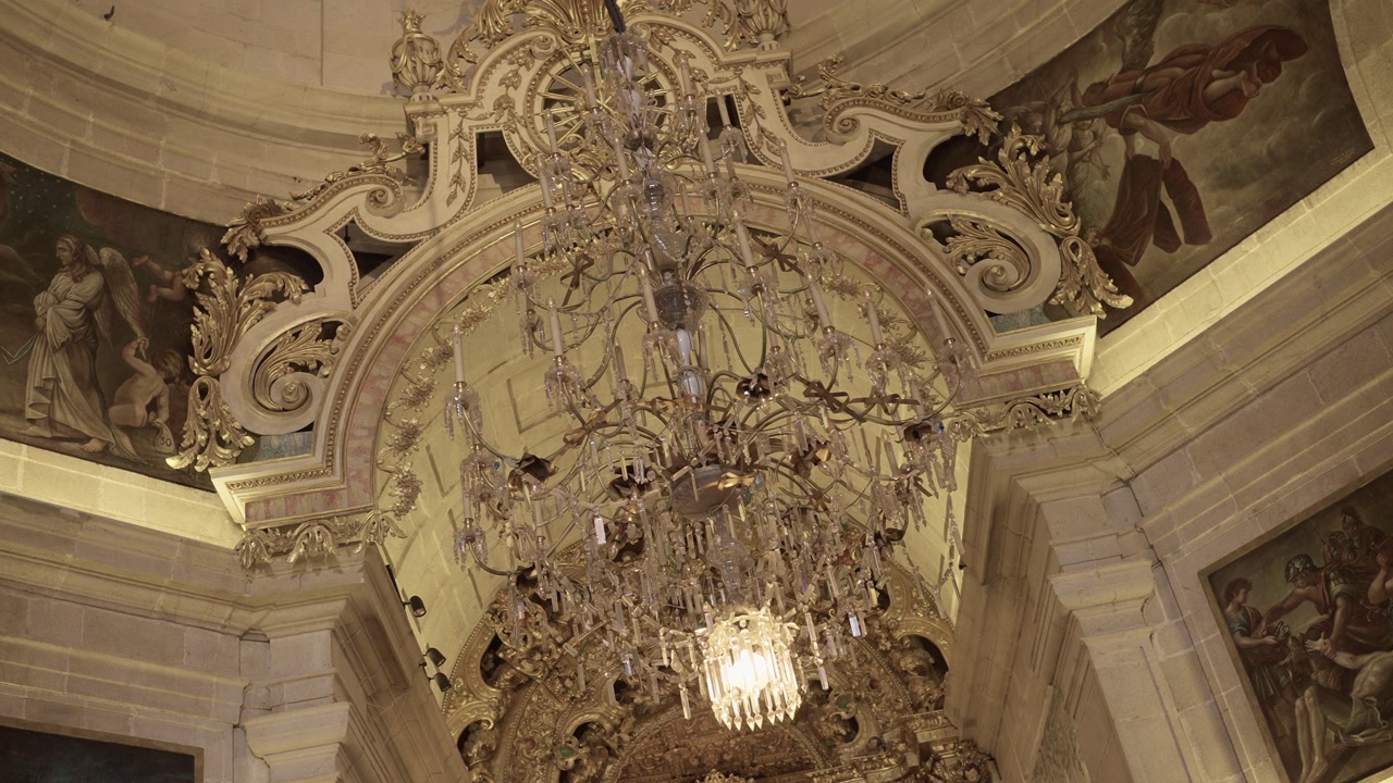 Baroque church ceiling with detailed chandelier and religious artwork