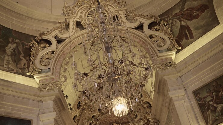 Baroque church ceiling with detailed chandelier and religious artwork