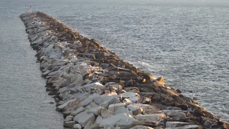 una larga ola blanca que se extiende hacia el mar al atardecer